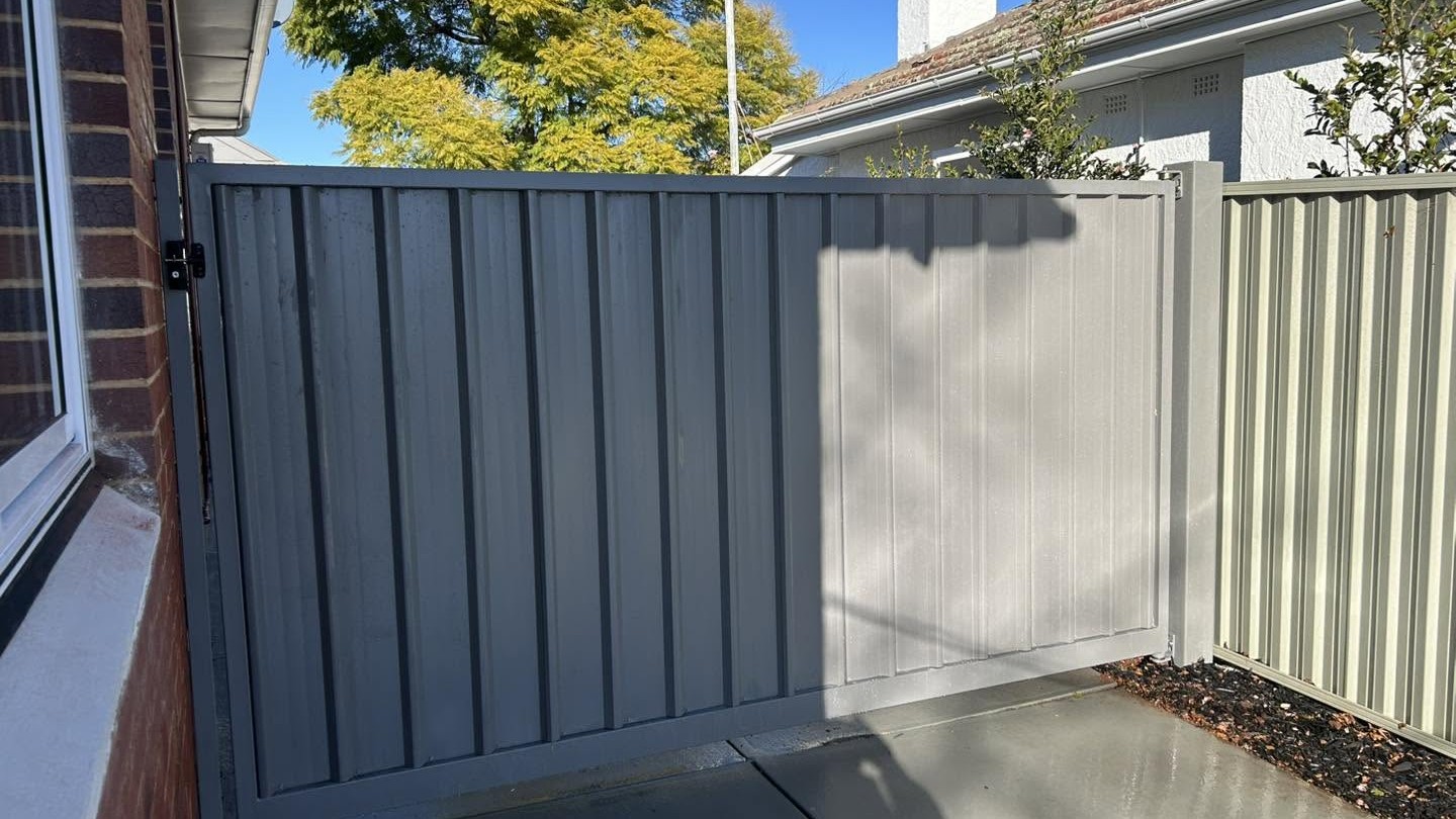 A cream Colorbond fence and gate against a brick home, built by Anesbury Fencing in Wagga Wagga