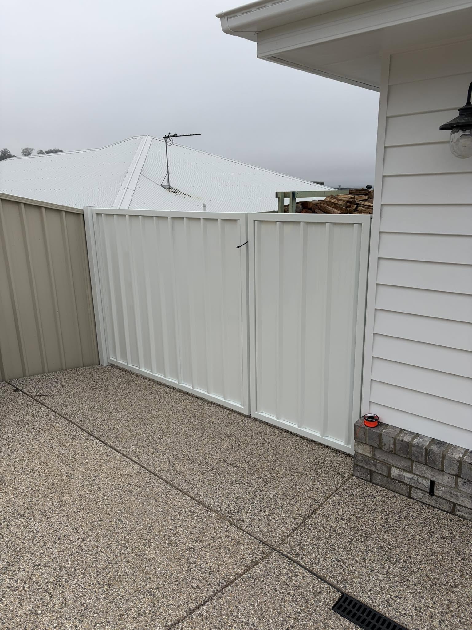 A cream Colorbond fence and gate on a fresh concrete path in Wagga Wagga