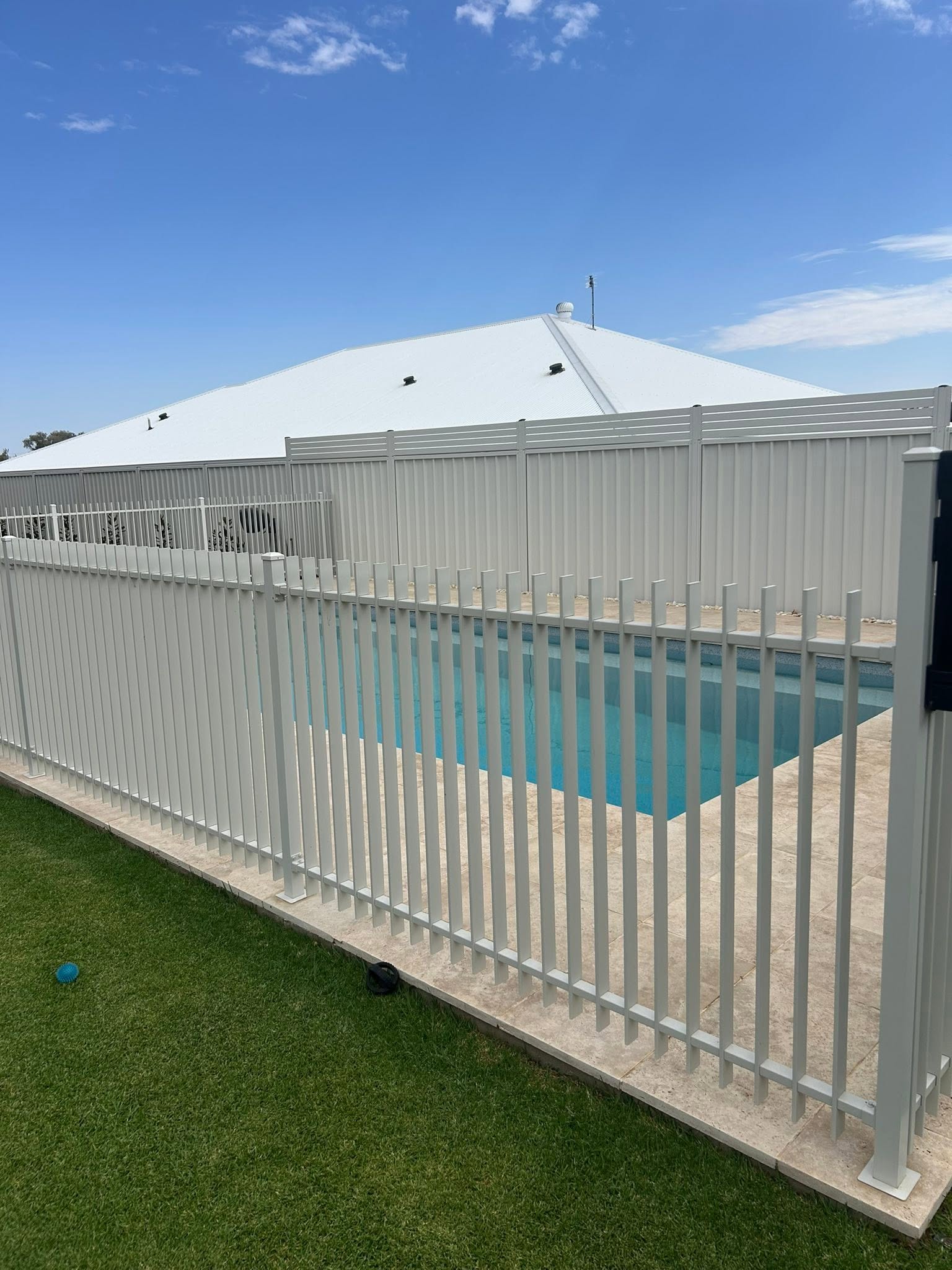 A white aluminium pool fence around a backyard pool – a real job by Anesbury Fencing & Construction in Wagga Wagga