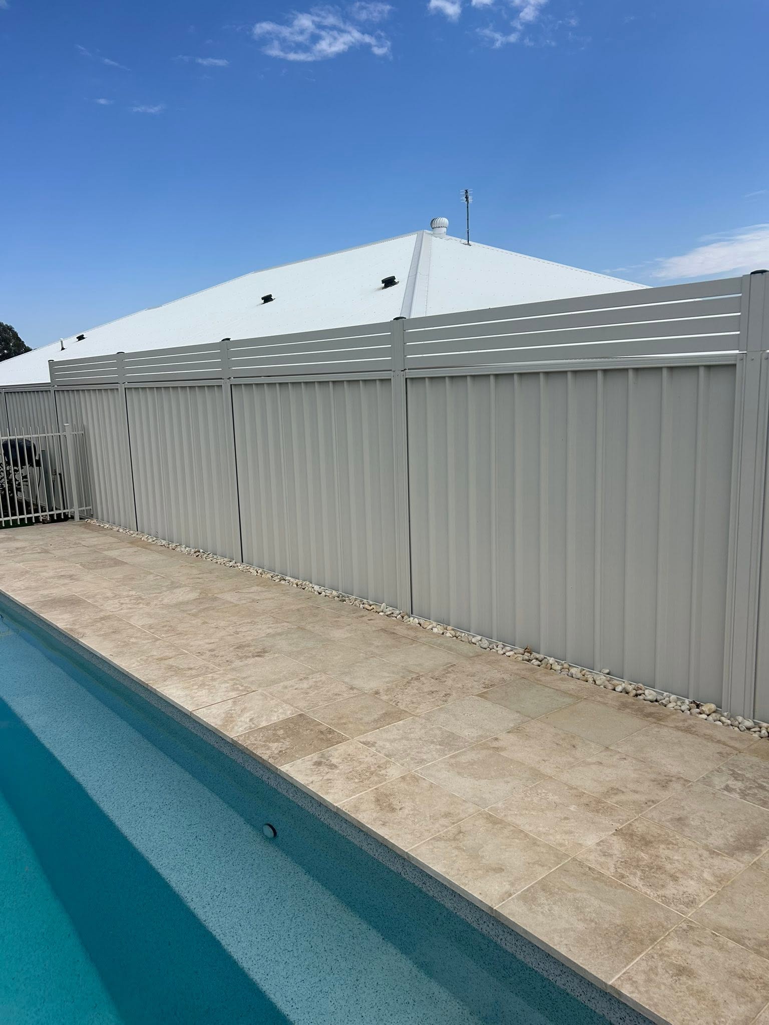 A white pool fence beside travertine paving – a real job by Anesbury Fencing & Construction in Wagga Wagga
