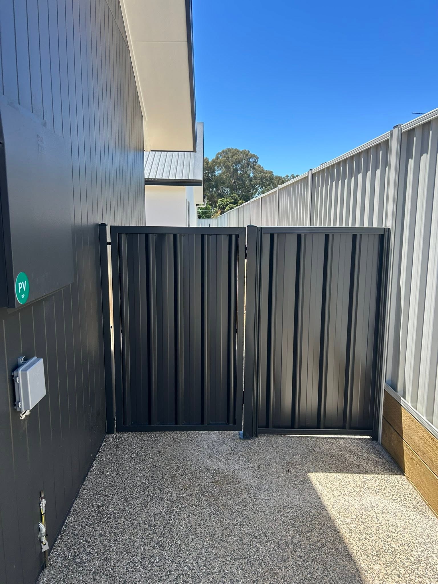 A dark grey Colorbond gate on exposed aggregate concrete – a real job by Anesbury Fencing & Construction in Wagga Wagga