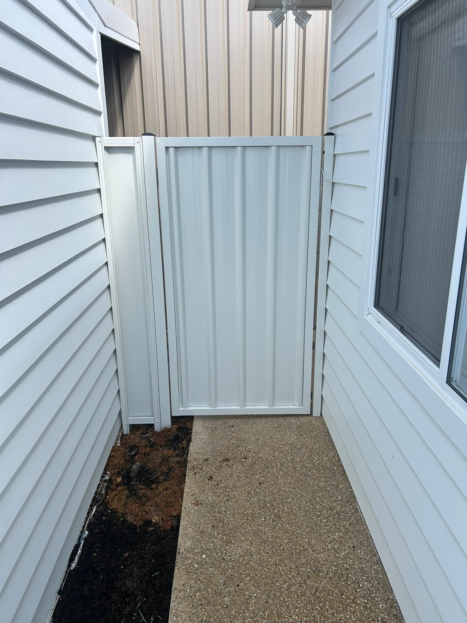 A cream Colorbond fence and gate at a weatherboard home – a real job by Anesbury Fencing & Construction in Wagga Wagga