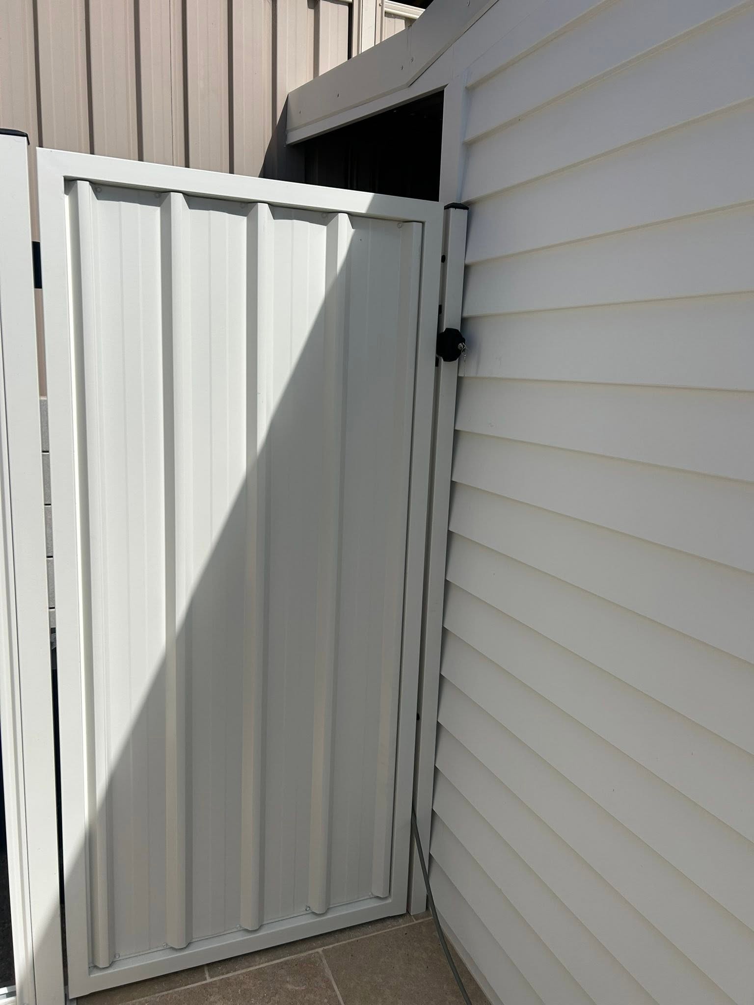 A cream Colorbond gate beside weatherboard cladding – a real job by Anesbury Fencing & Construction in Wagga Wagga