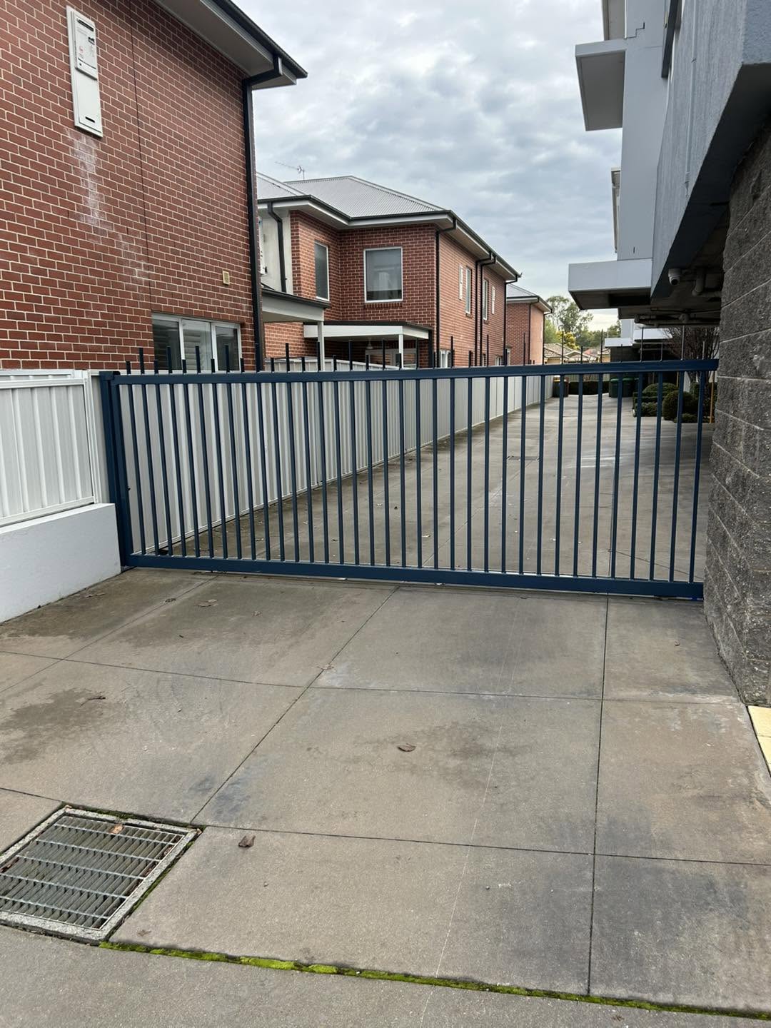 A blue-grey pool gate and fence beside a driveway