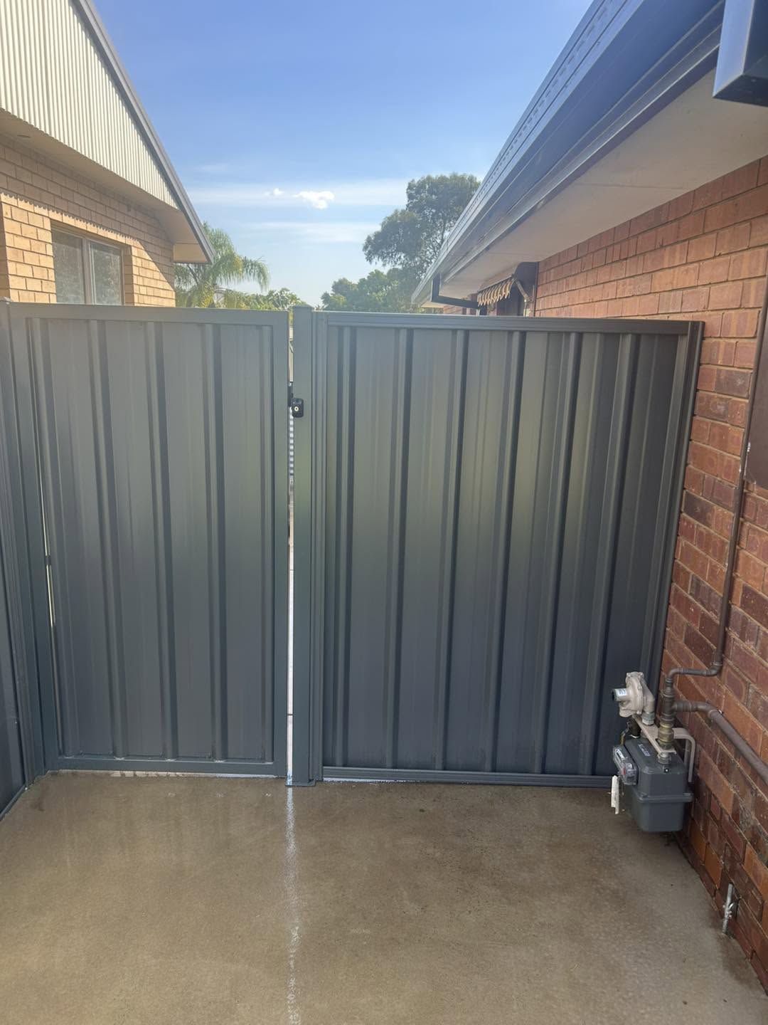 Grey Colorbond double gates hung between brick piers in Wagga Wagga